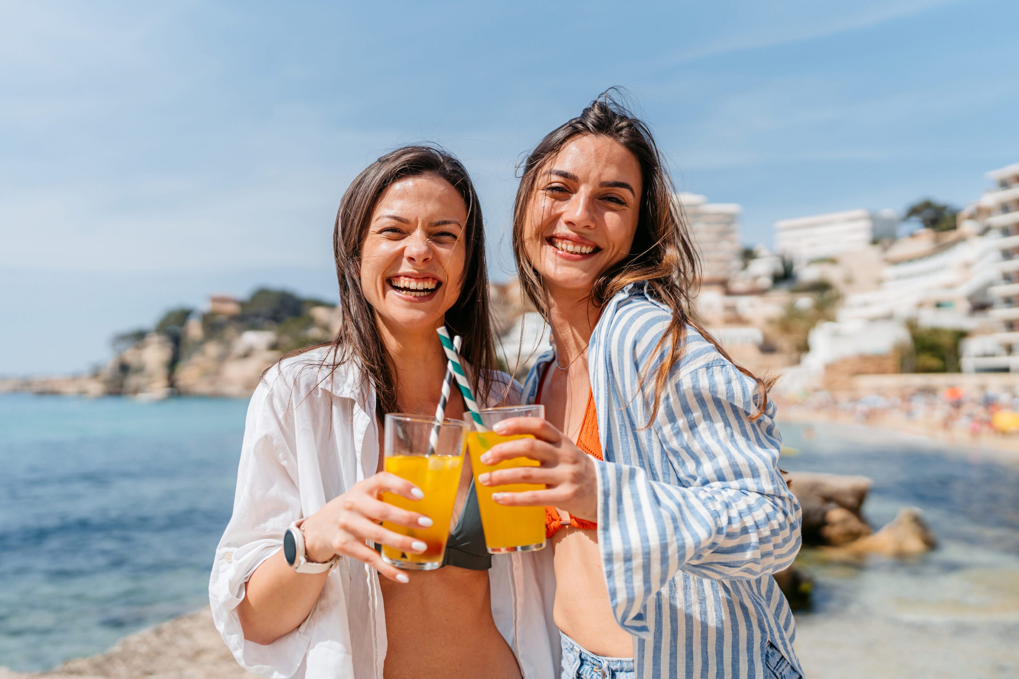 Two women smiling with orange drinks.